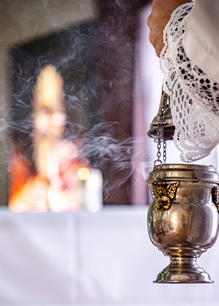 Close-up of a brass incense burner emitting smoke during a sacred ritual indoors.